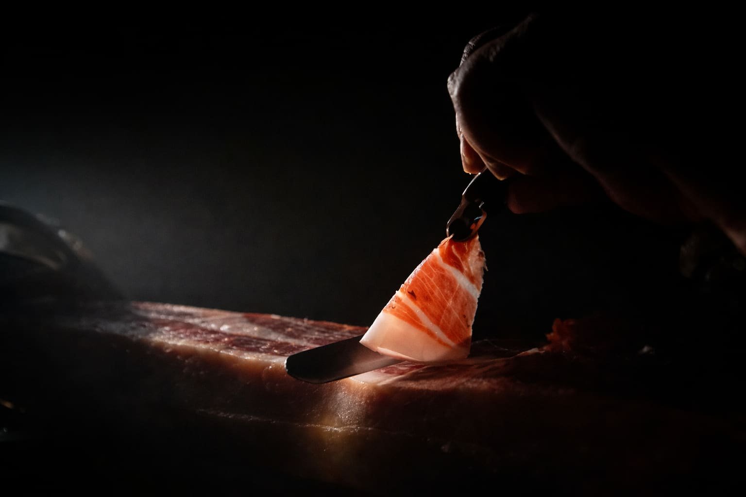 Découpe fine d'une tranche de jambon ibérique à la lumière