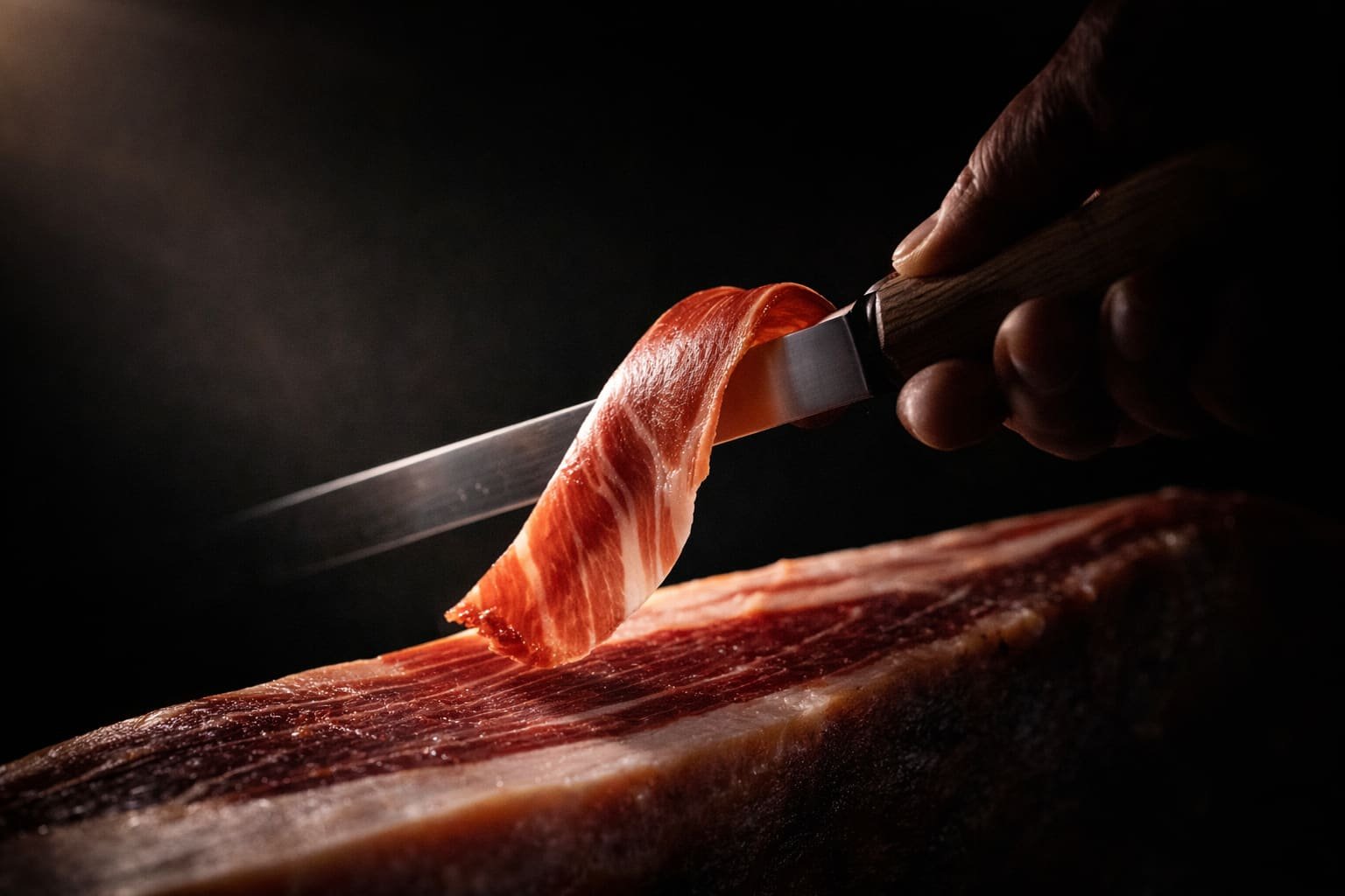 Main tenant une tranche de jambon ibérique, geste du maître coupeur
